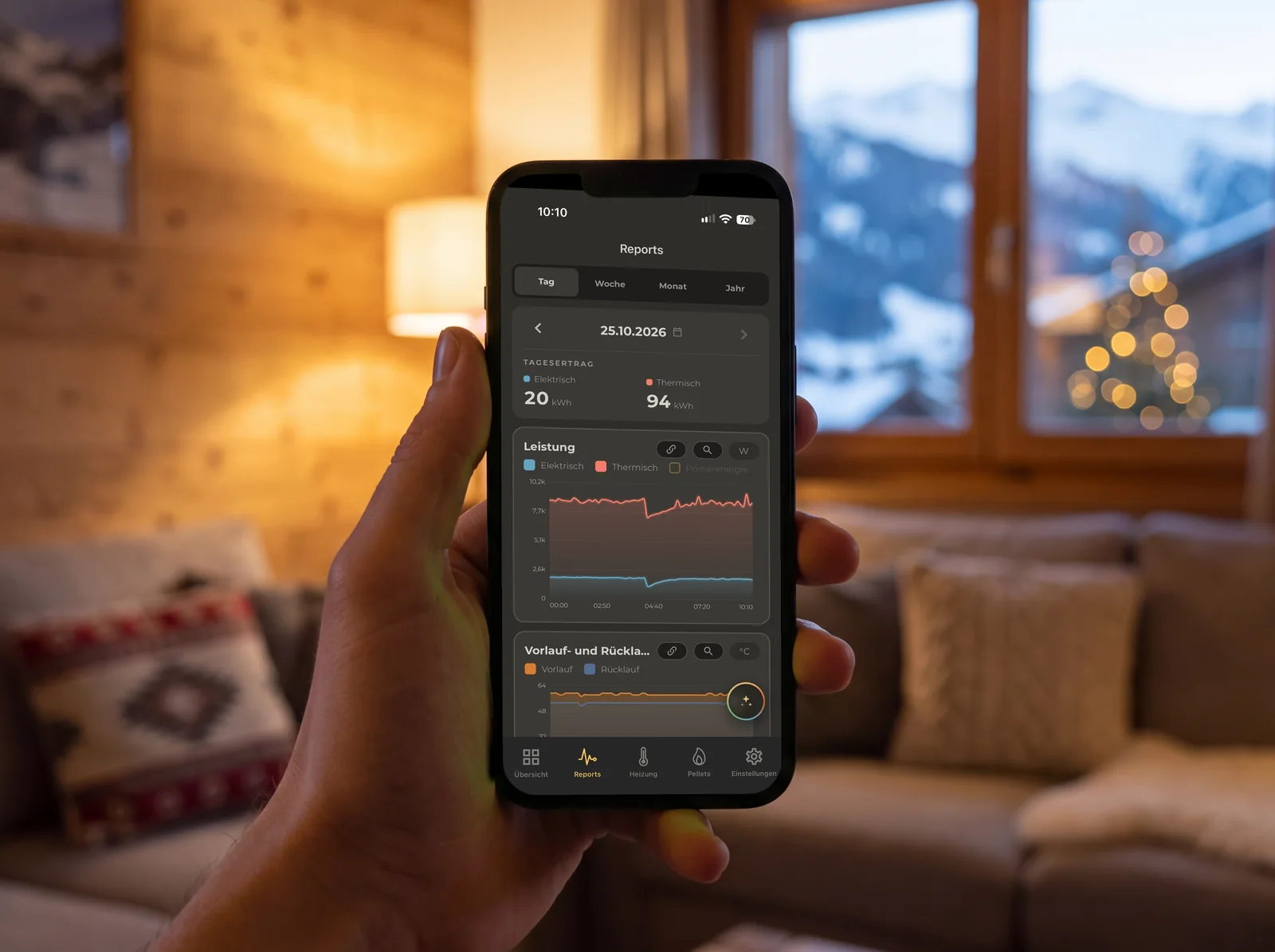 Hand holding a smartphone in a living room on a winter evening, the COR.app daily report on the display